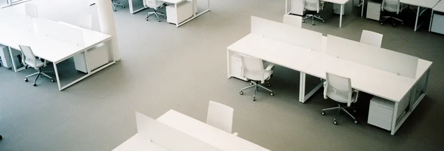 Vue aérienne d'un bureau moderne avec plusieurs écrans affichant des graphiques colorés et un analyste examinant des données marketing