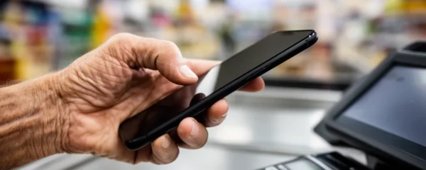 Smartphone moderne dans main humaine montrant un geste de paiement biométrique dans un contexte commercial